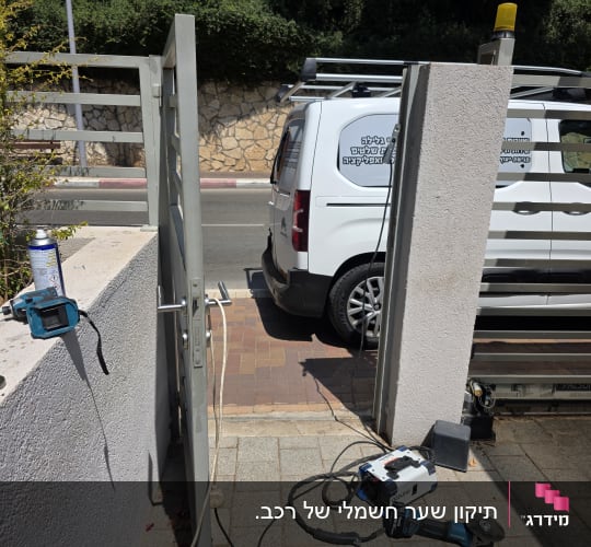 שער חשמלי עם כלי עבודה ורכב שירות ברקע